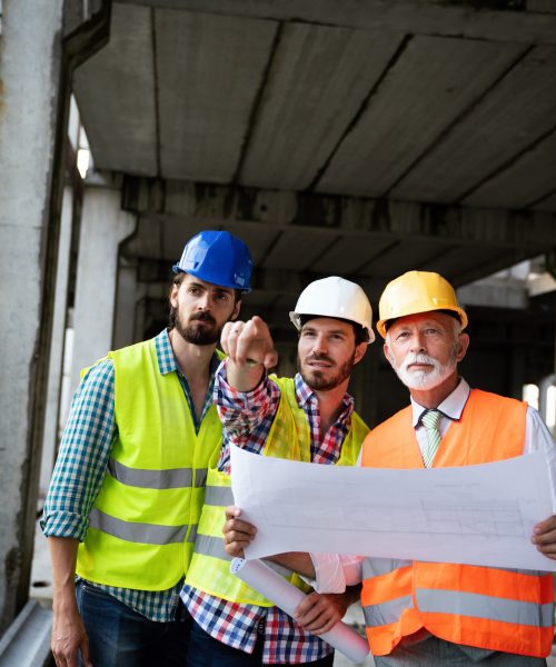 Confident team of architects and engineers working together on construction site